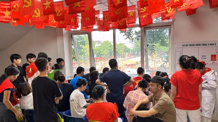 Người nhà bệnh nhân theo dõi lễ diễu binh diễu hành A80 qua cửa sổ bệnh viện. Ảnh: Thùy Linh