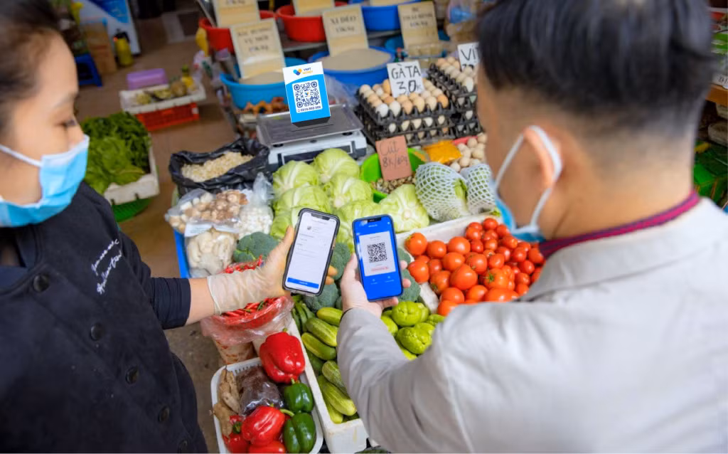 Khách hàng và các tiểu thương giao dịch trực tuyến không dùng tiền mặt qua mã QR tại chợ Hạ Long 2.