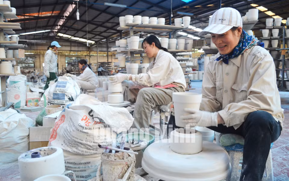 Công nhân của Công ty gốm sứ Quang Vinh thực hiện công đoạn tiện trong quy trình sản xuất sản phẩm (1-2015). Ảnh: Nguyễn Hoa