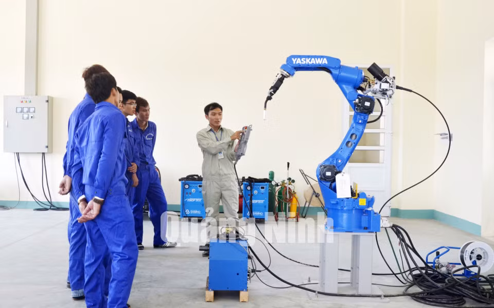 Giáo viên hướng dẫn sinh viên thực hành sử dụng robot hàn tự động. Ảnh: Phương Thúy