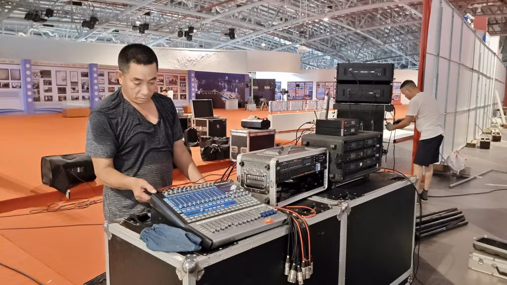 Công nhân kỹ thuật gấp rút hoàn thiện việc lắp đặt trang thiết bị âm thanh, ánh sáng phục vụ không gian triển lãm.