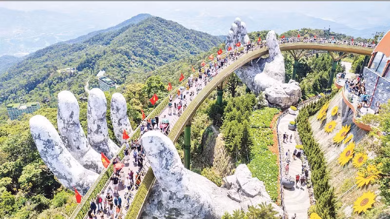 Du khách thưởng lãm khung cảnh công trình "Cầu Vàng" rợp bóng cờ đỏ sao vàng. (Ảnh: PHAN HẢI TÙNG LÂM)