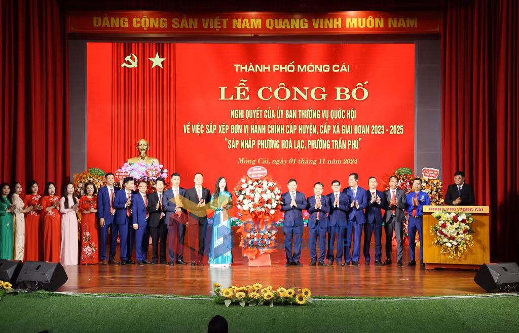 2024-11_Móng Cái Công bố Nghị quyết của Ủy ban Thường vụ Quốc hội về sáp nhập phường Trần Phú và phường Hòa Lạc- Phó chủ tịch UBND tỉnh Nghiêm Xuân Cường tặng hoa chúc mừng. Ảnh: Hữu Việt