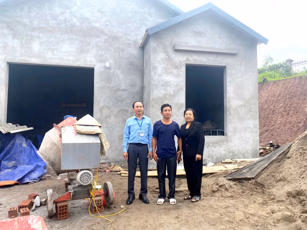 Anh Chíu Văn Dùng (thôn Tràng Tây, xã Đông Hải) cùng lãnh đạo địa phương trước ngôi nhà đang trong quá trình hoàn thiện.