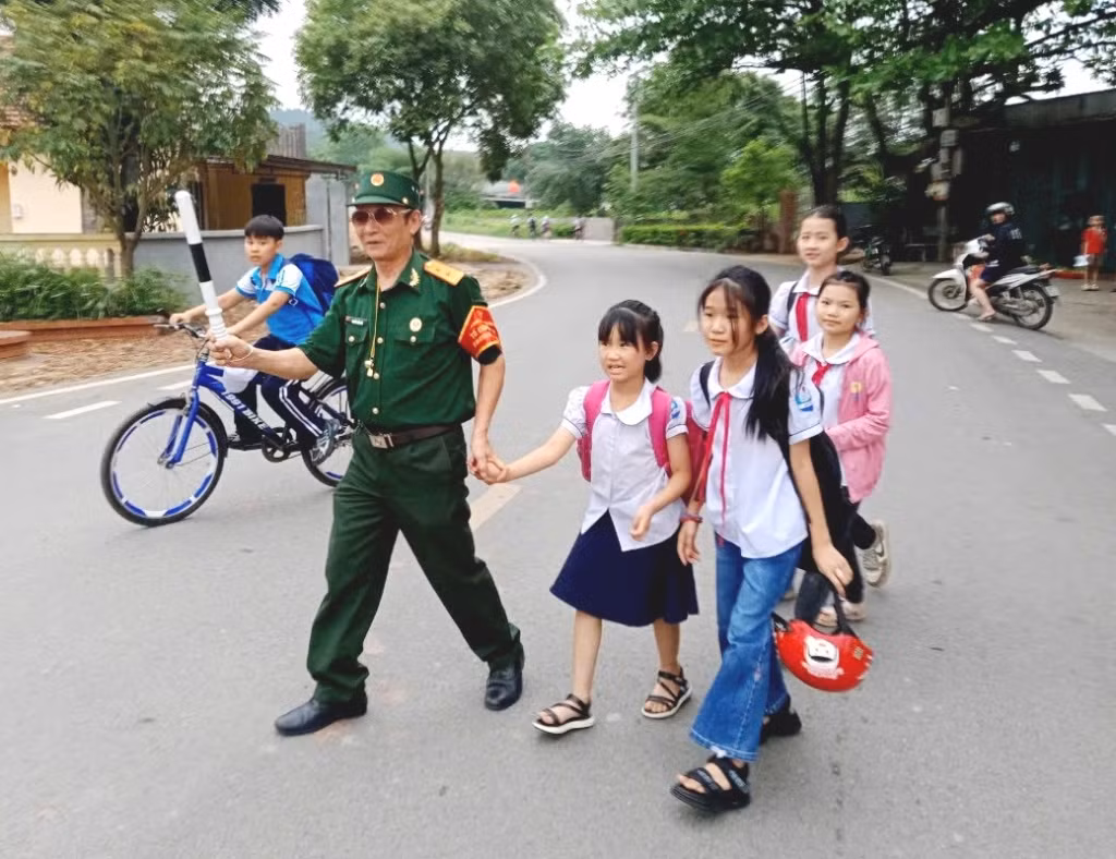 Hội viên CCB xã An Sinh (TP Đông Triều) dẫn học sinh Trường Tiểu học An Sinh qua đường.