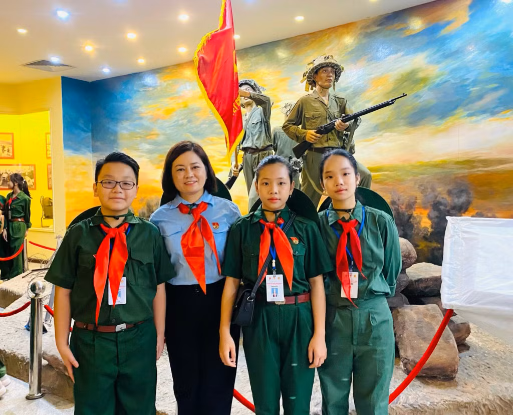 3 thiếu nhi Quảng Ninh (từ trái qua: Cù Thế Tùng, Đinh Thu Trà, Cao Ngọc Minh Thư) cùng cô giáo Đinh Thị Hợi, Giáo viên Tổng phụ trách Đội trường Tiểu học Đông Ngũ II (huyện Tiên Yên) phụ trách đoàn.