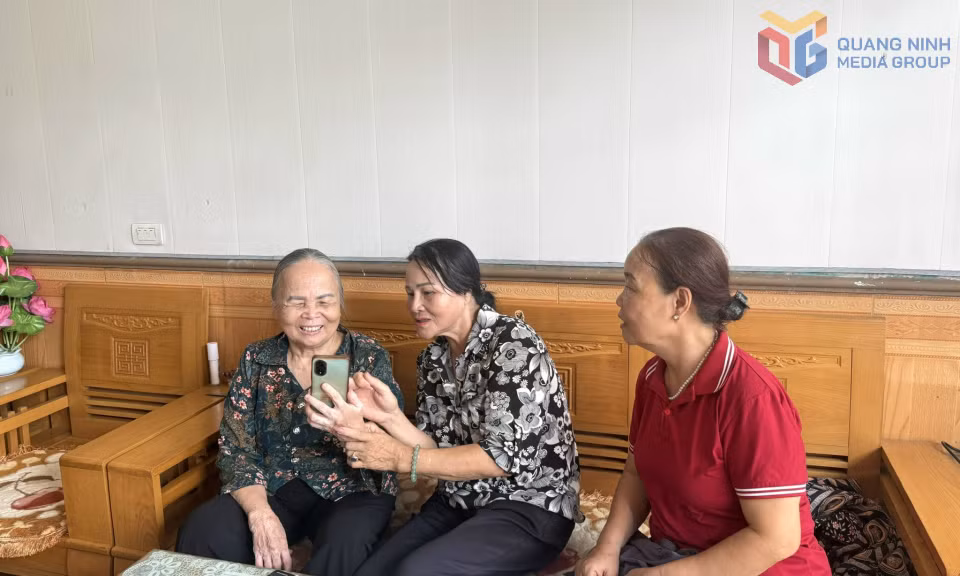 Bà Phạm Thị Múi (bên trái) được hướng dẫn cài đặt và nhận trợ cấp hưu trí xã hội qua tài khoản ngân hàng.