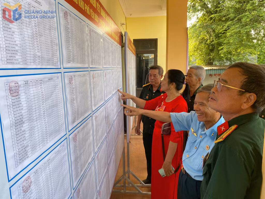 Cử tri đại diện hộ gia đình khu phố Yên Đức 1, phường Hoàng Quế, cẩn trọng kiểm tra danh sách trước khi bước vào khu vực bỏ phiếu.
