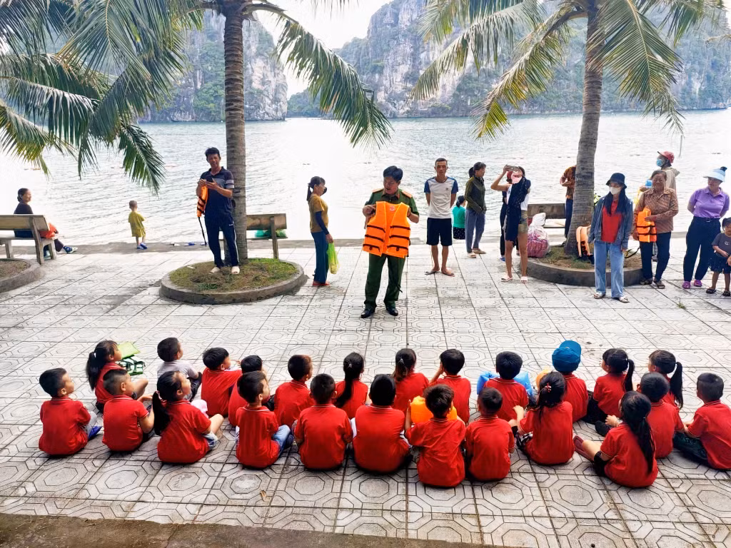 Công an xã Thắng Lợi hướng dẫn trẻ em trên địa bàn cách mặc áo phao. Ảnh: Quyền Hưng (CTV)