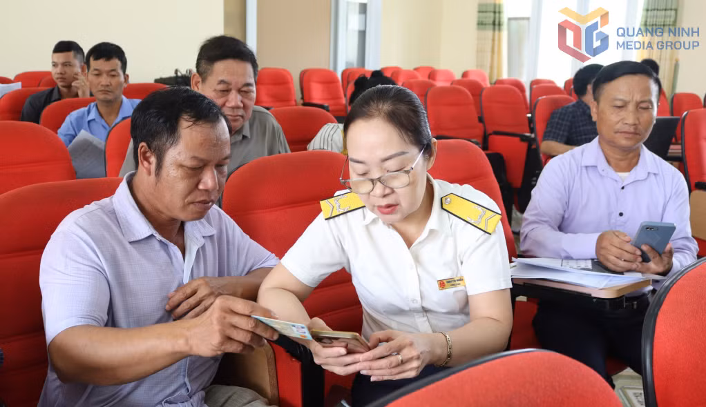 Người dân xã Quảng Tân được cán bộ thuế hướng dẫn cài đặt ứng dụng eTax Mobile.