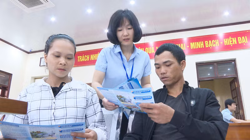 Cán bộ Trung tâm Hành chính công huyện phát tờ rơi hướng dẫn người dân nộp hồ sơ qua mạng.