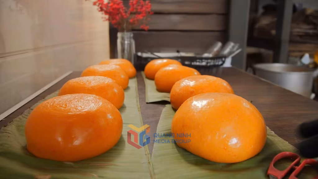Những chiếc bánh giầy giã tay nóng hổi, tròn trịa, màu cam đỏ bóng loáng được đặt lên trên lá chuối xanh rất đẹp mắt.