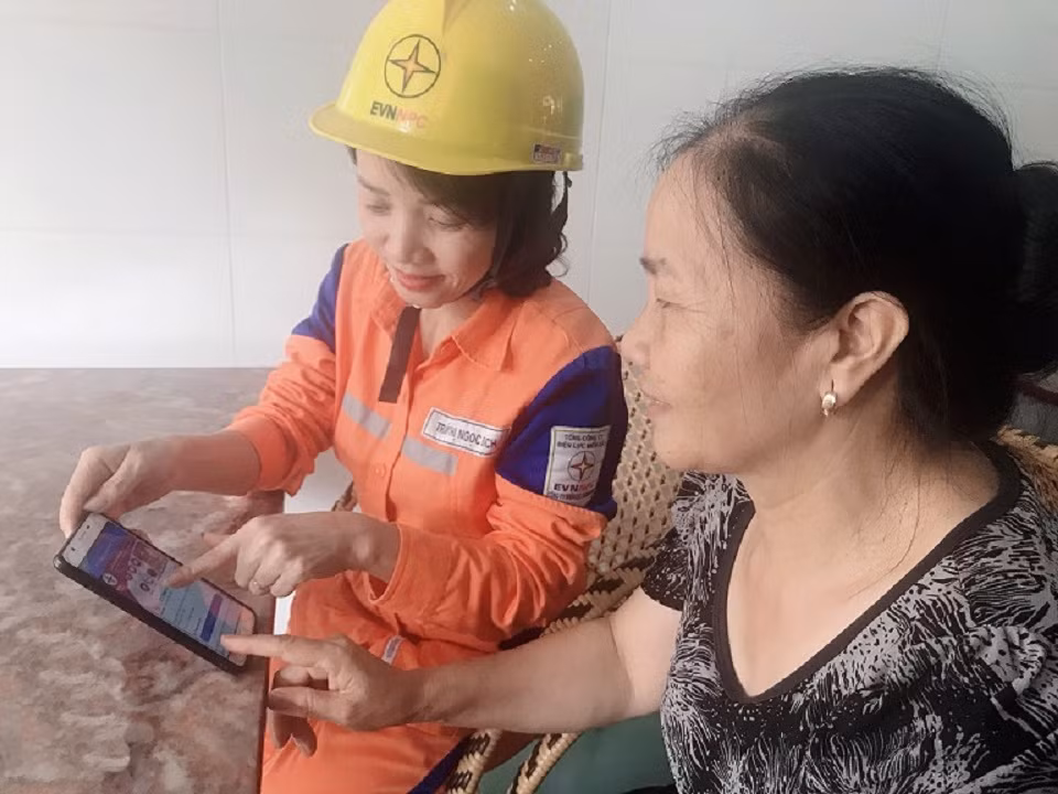 Công nhân Điện lực TP Hạ Long hướng dẫn khách hàng thanh toán tiền điện online qua ứng dụng EVNNPC CSKH trên điện thoại thông minh.