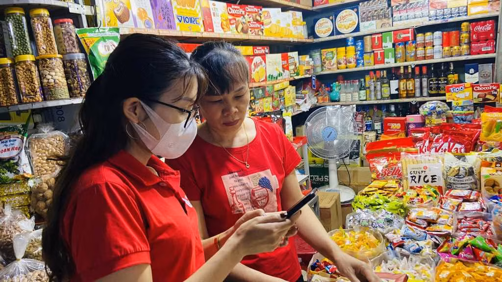 Viettel Quảng Ninh hướng dẫn chủ cửa hàng tạp hóa tại Chợ Hạ Long I cài đặt ứng dụng Viettel Money. Ảnh: Hoàng Nga