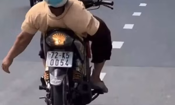 Người đàn ông cụt tay phải lái xe máy, thả tay còn lại như diễn xiếc trên đường