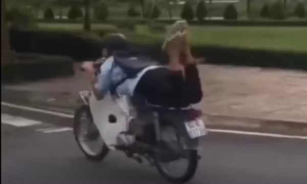 Nam thanh niên nằm trên yên điều khiển xe máy
