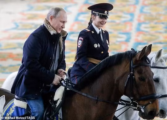 Ông Putin cưỡi một con ngựa nâu bên cạnh đoàn kỵ nữ cưỡi ngựa trắng Ảnh: TASS