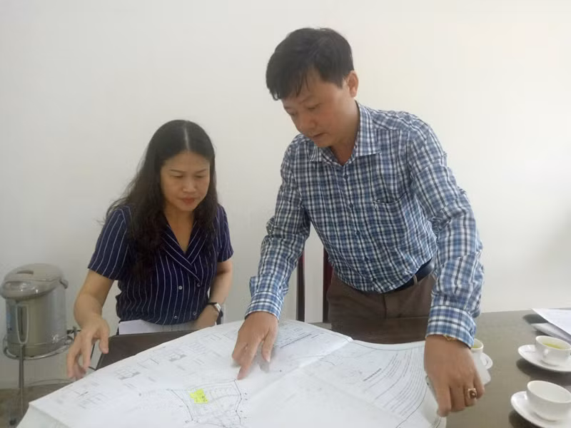 Chủ tịch UBND phường Đức Chính Nguyễn Thị Thu Hằng và cán bộ địa chính phường chỉ cho phóng viên Bản đồ quy hoạch tổng mặt bằng sử dụng đất của Dự án. Ảnh: Thu Nguyệt